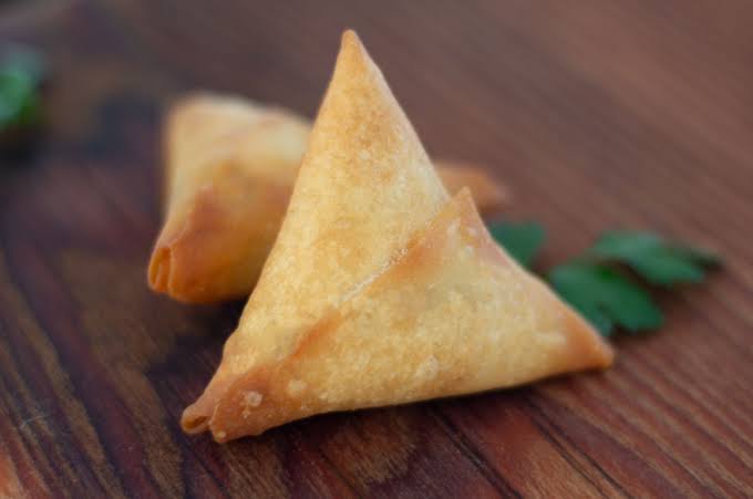 Golden samoosas on a wooden table